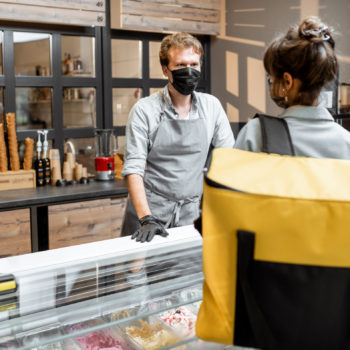 Cover image: 5 ways to rethink your swag strategy -Deli clerk wearing a mask helping a customer
