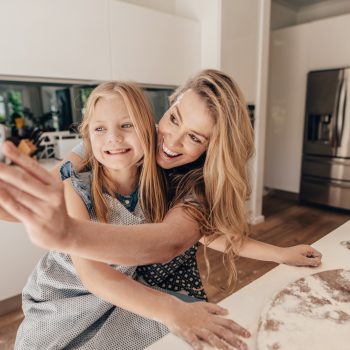 mom and daughter taking a selfie, smiling while baking
