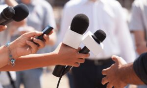 Several hands outstretched holding microphones