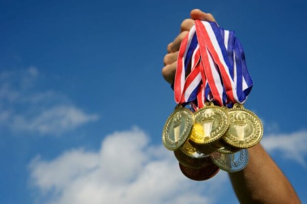 Outstretched hand holding a group of gold medals