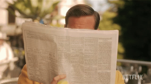 Man reading newspaper and looking over the top of the page