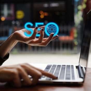 Person typing on laptop with the word "SEO" in hand