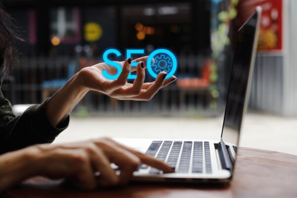 Person typing on laptop with the word "SEO" in hand