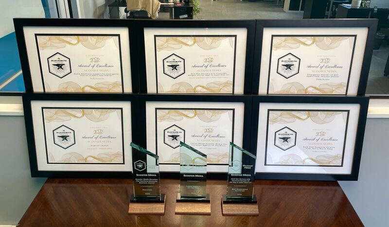 Three Blacksmith Awards and six Awards of Excellence displayed on a table