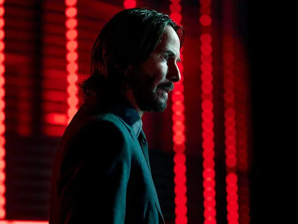 John Wick (Keanu Reaves) standing in front of a wall of red lights