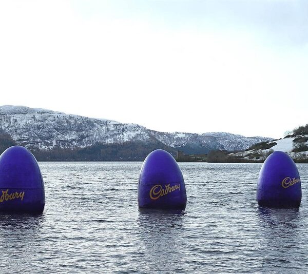 Three giant purple Cadbury eggs placed in a lake to look like the Loch Ness Monster