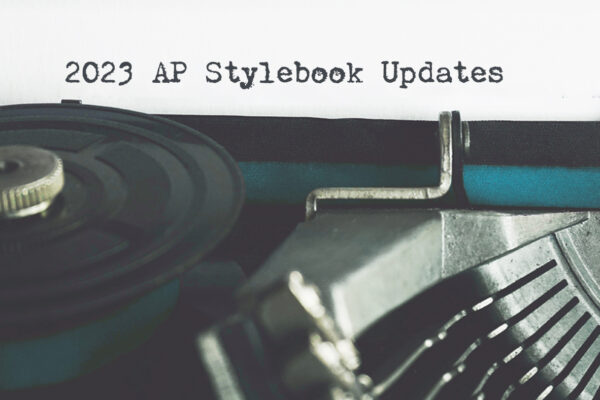 A typewriter with a teal ribbon in front of a sheet of paper with "2023 AP Stylebook Updates" typed on it