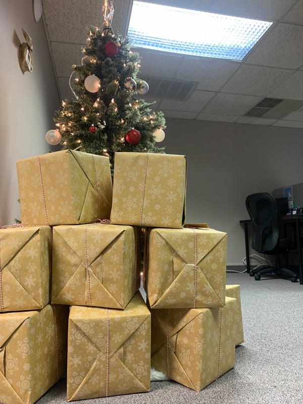 Golden boxes of client gifts underneath a tree.